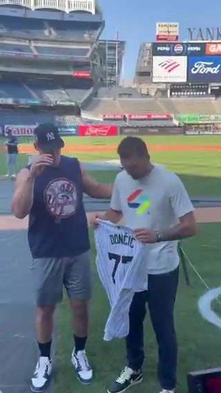 东契奇接过纽约洋基队球星阿隆-贾奇赠送的洋基队77号球衣